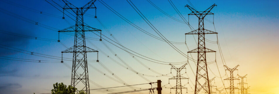 Sun setting behind the silhouette of electricity pylons